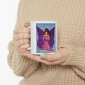 Ceramic mug with purple fairy artwork, held in hands with sweater sleeves