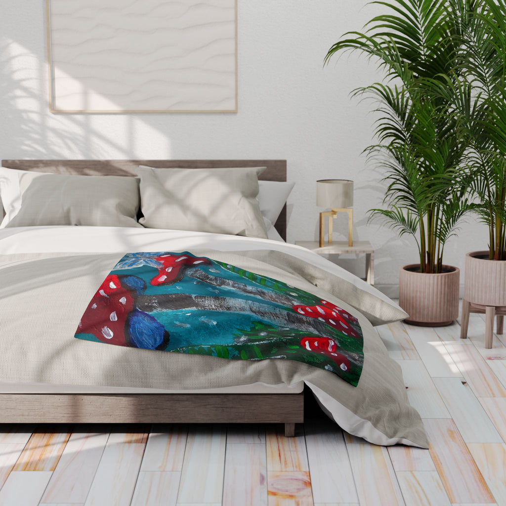 Fleece blanket spread on a bed with teal, blue, gray, green, and red mushroom artwork
