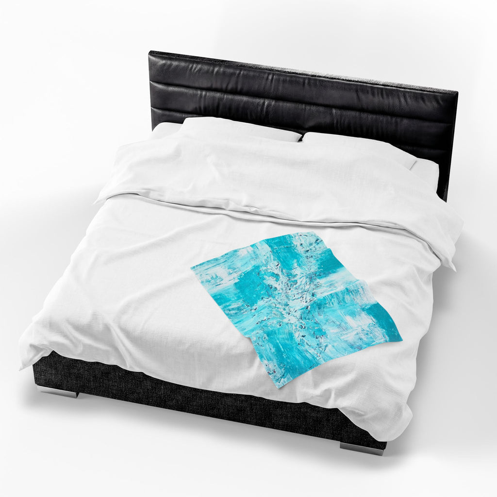 Turquoise abstract plush blanket with blue square graphic centered on white bedding cover