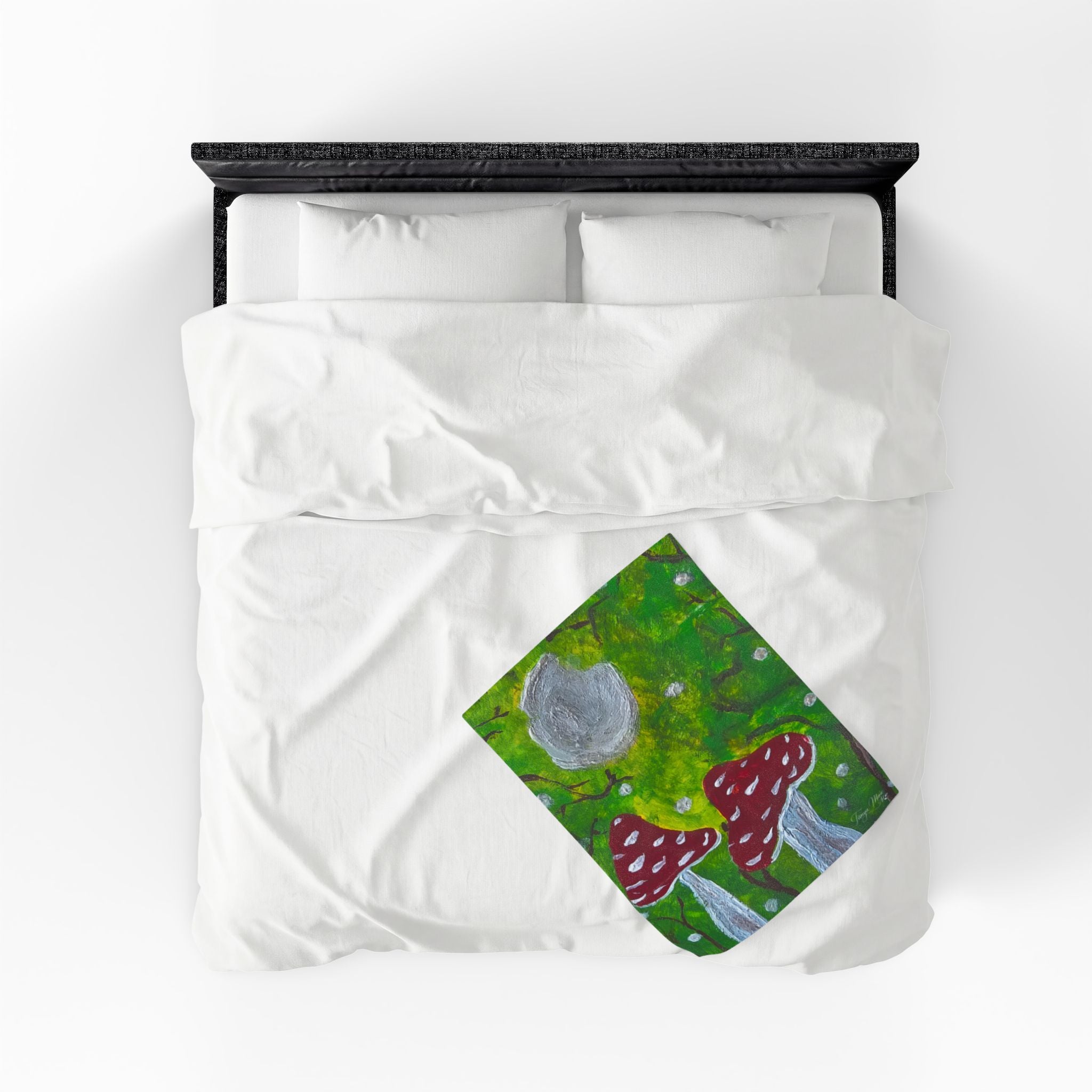 Velveteen blanket corner showing green forest print with red spotted mushrooms