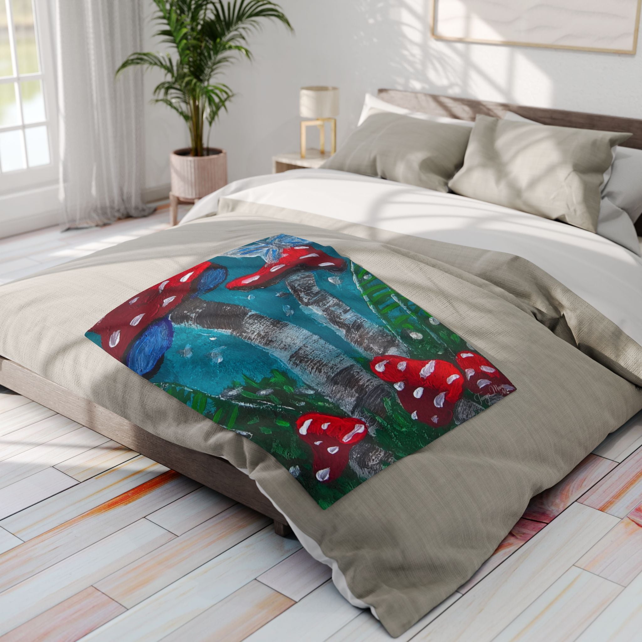 Fleece blanket folded on bed, showing red mushrooms on teal-blue and dark gray background