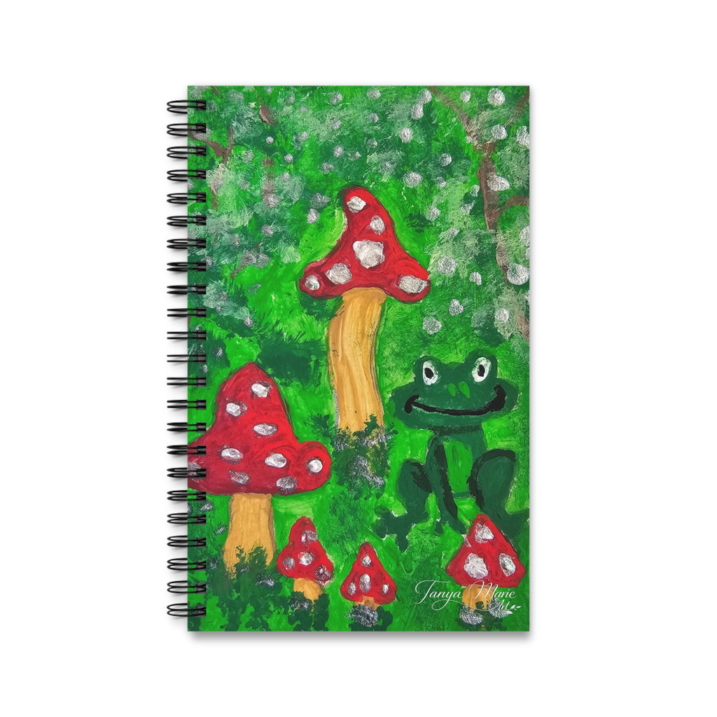 Spiral journal with green whimsical forest cover, red mushrooms, and a frog character.