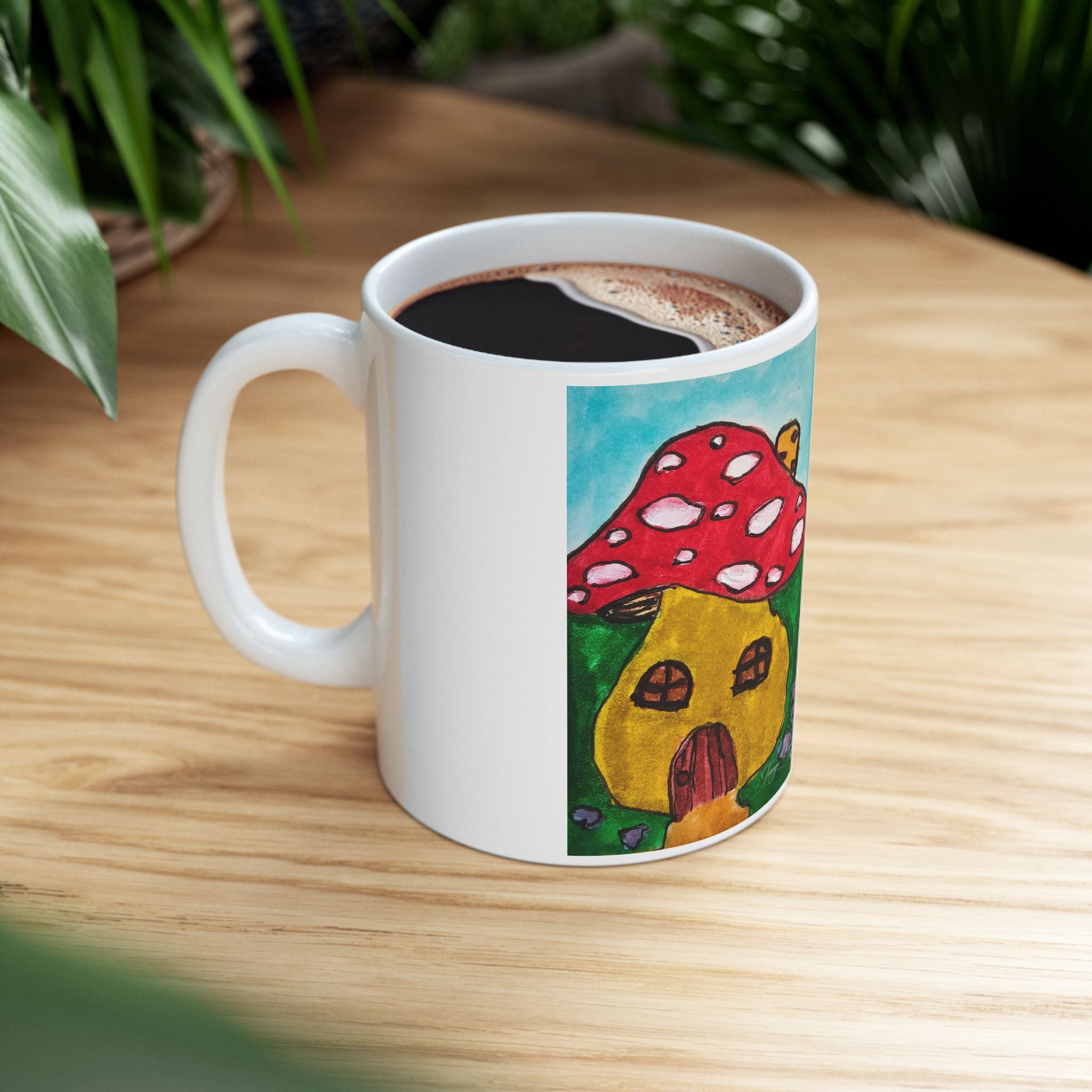 White ceramic mug with red mushroom house art, filled with tea or coffee