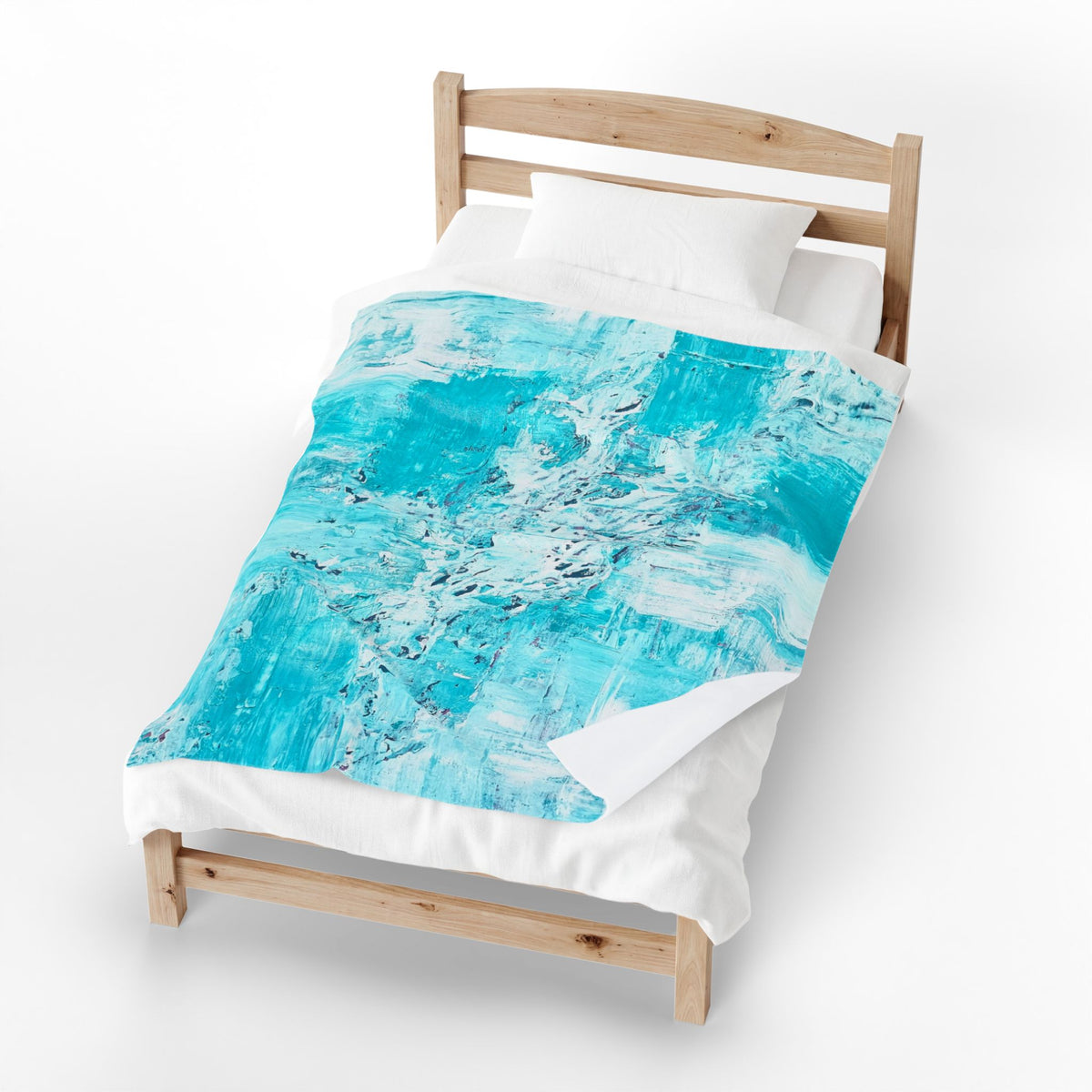 Velveteen plush blanket on bed with turquoise abstract ocean print over white bedding