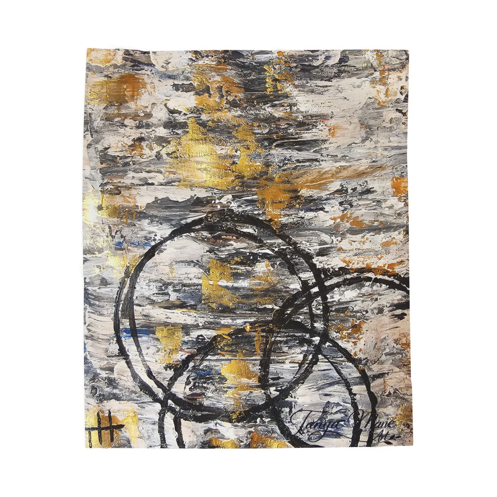 Abstract plush blanket showing charcoal circle and swoosh lines with gold accents on gray
