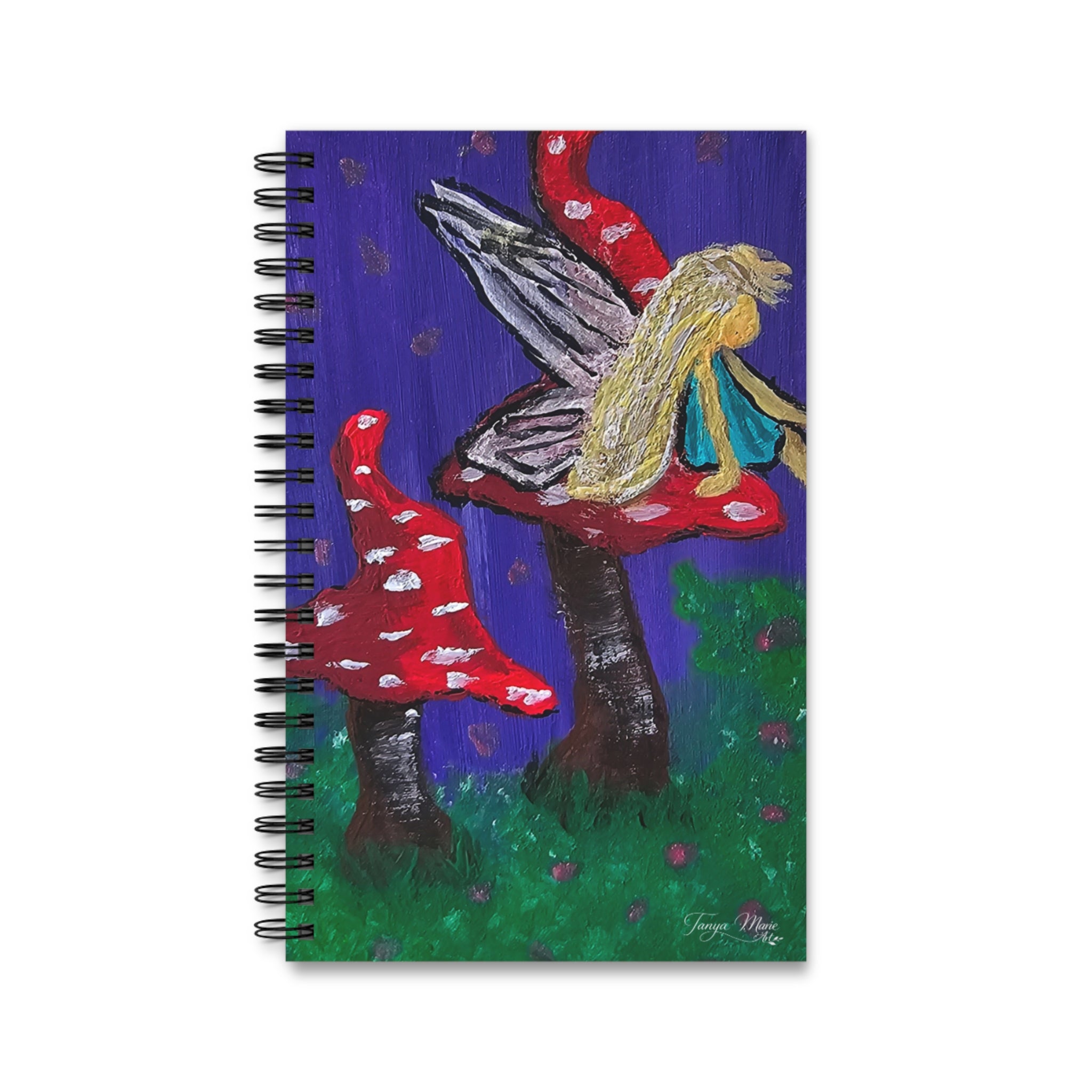 Spiral notebook with fairy and red mushrooms illustration on a purple-green cover.