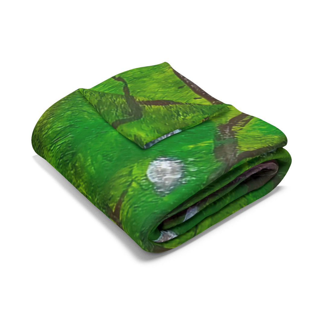 Folded green fleece blanket with red mushroom and gray cap artwork