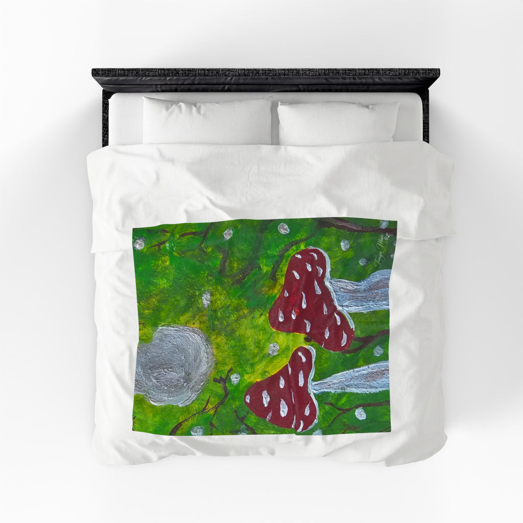 Plush velveteen blanket with green woodland panel, red mushrooms, and gray stone