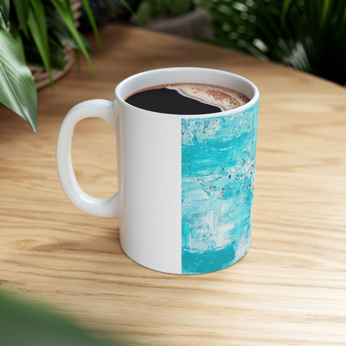 White ceramic mug with turquoise abstract ocean panel and handle, filled with coffee