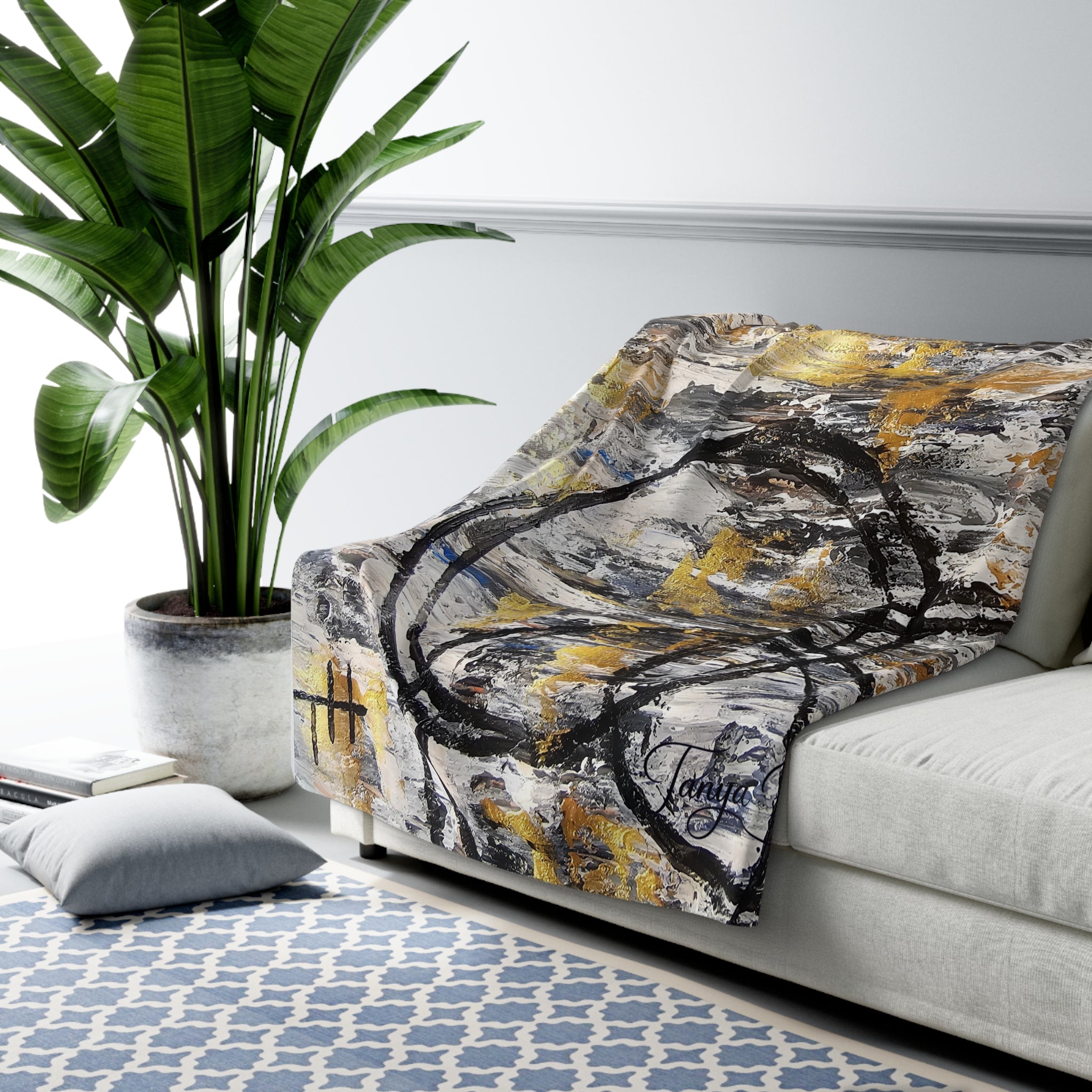 Sherpa throw blanket with abstract gold and charcoal brushstroke print on a couch