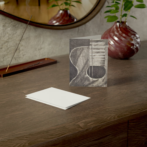 Acoustic guitar sketch greeting card, black-and-gray guitar design on front with blank white card.