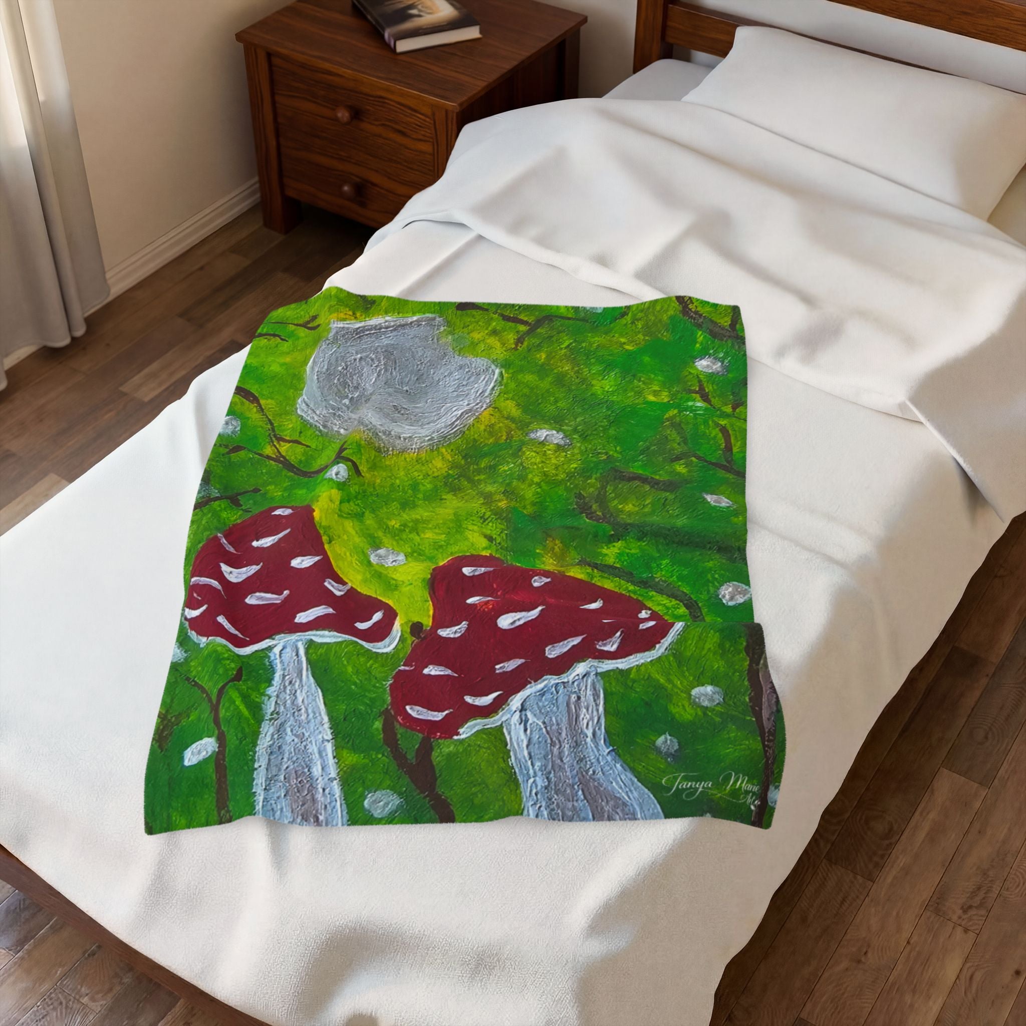 White plush blanket with green forest artwork and red mushroom caps, gray center moon.