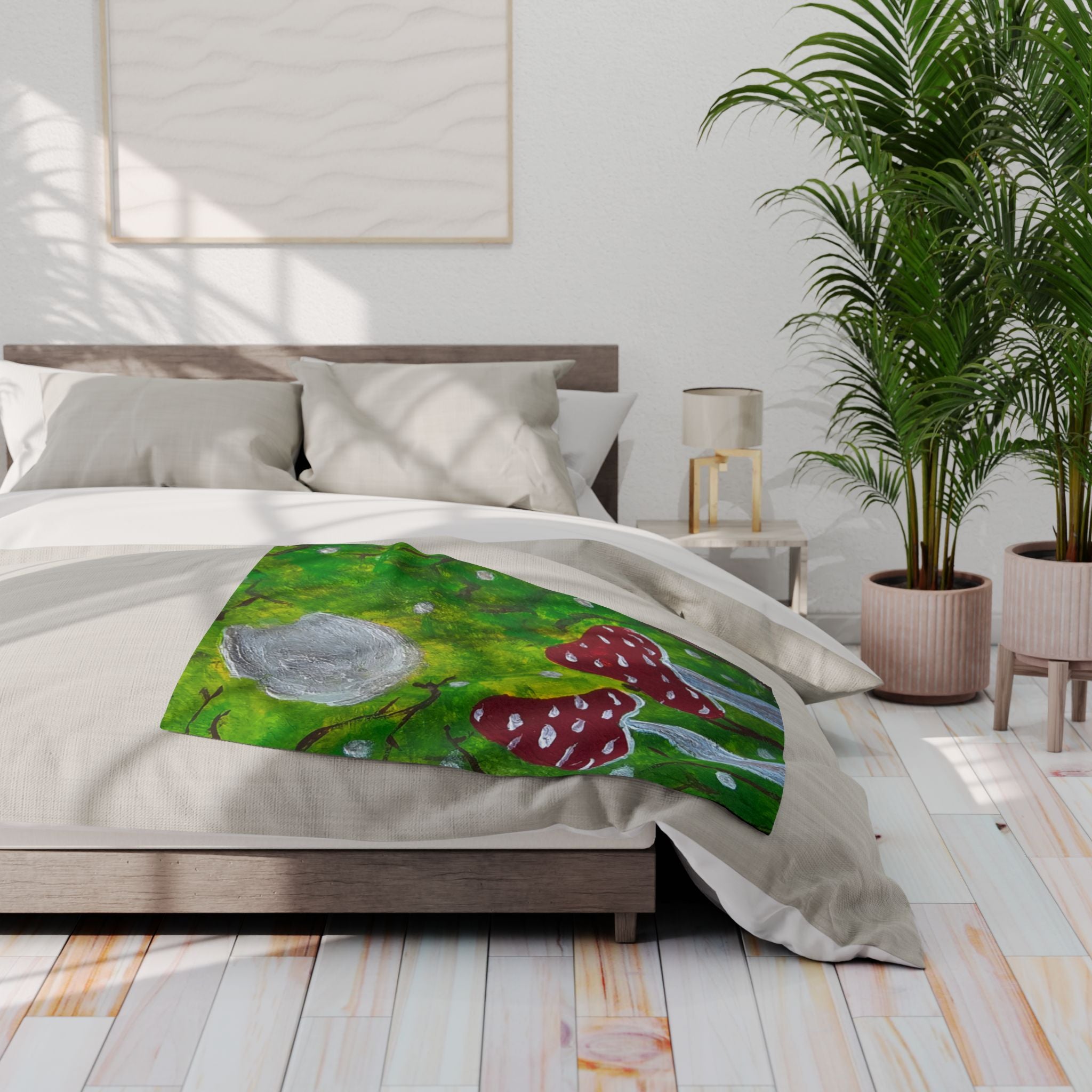 Fleece blanket on a bed, showing green forest with gray moon and red mushroom artwork