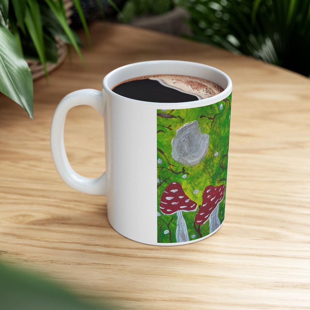 Ceramic mug filled with coffee, showing green woodland and red toadstool artwork