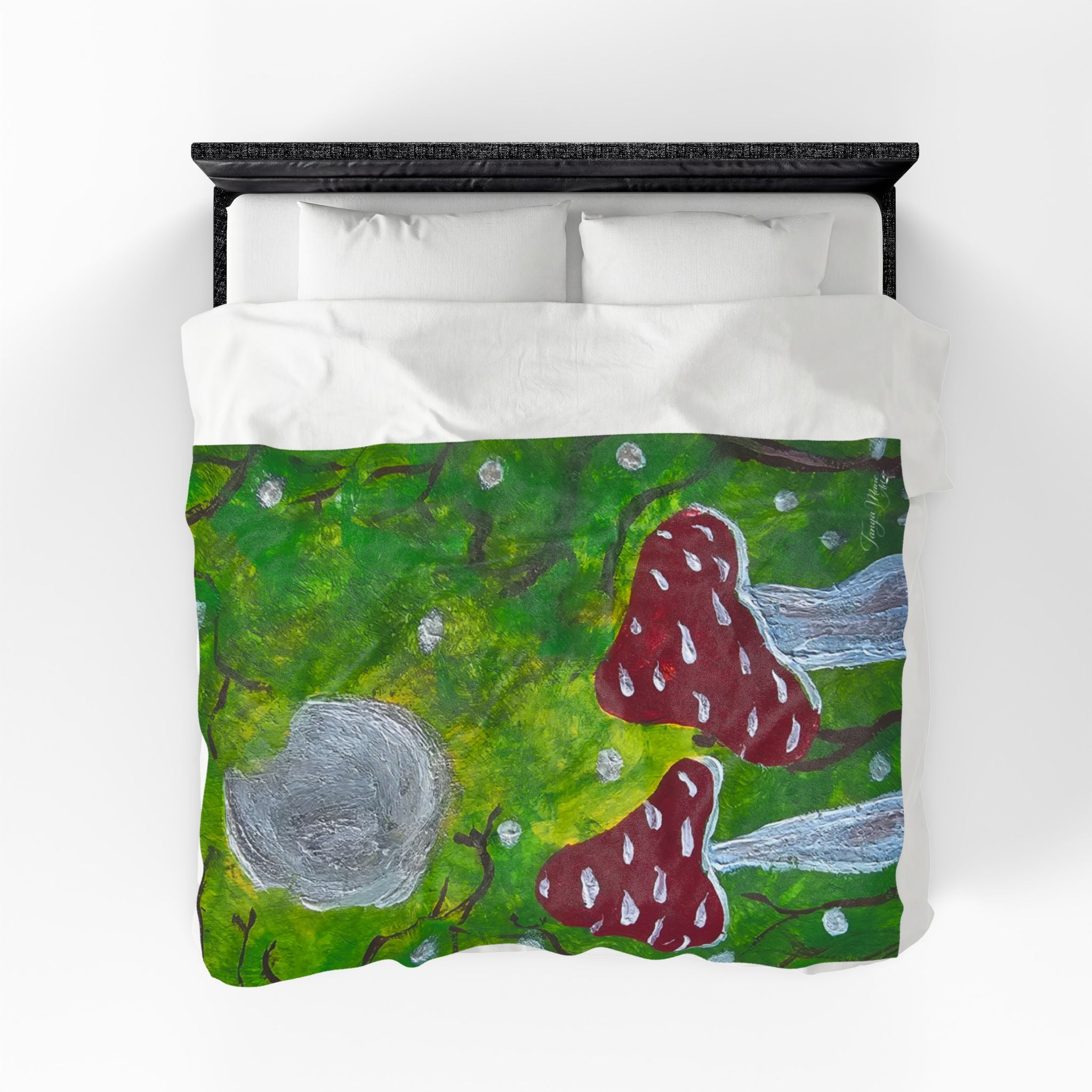 Velveteen blanket on bed, green forest print with red spotted mushrooms