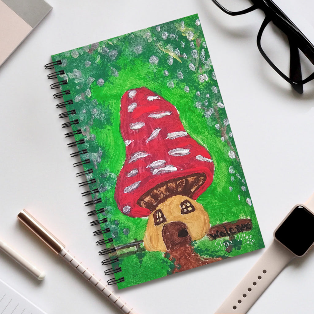 Spiral journal with green cover featuring red mushroom and fairy house artwork