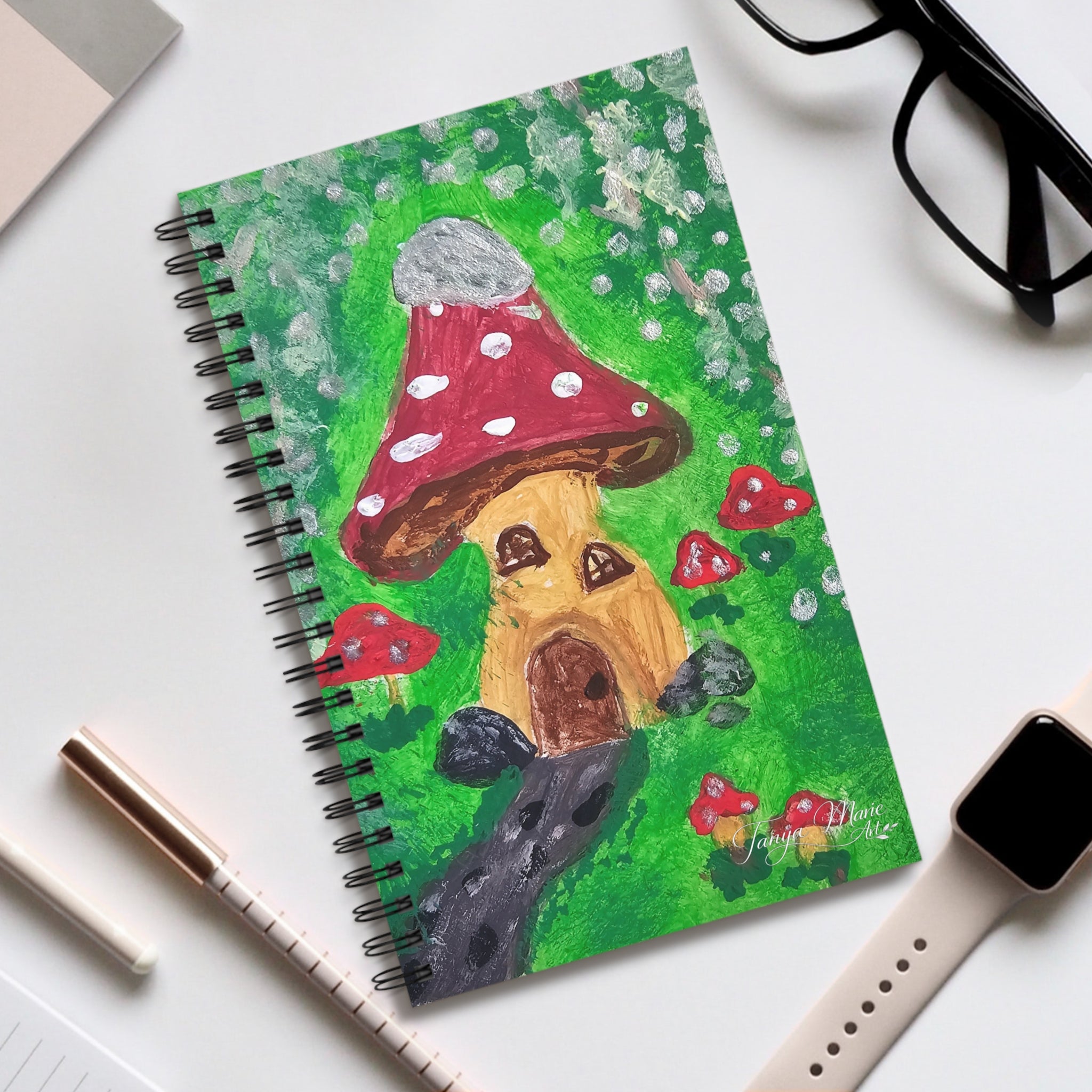 Spiral notebook with fairy garden mushroom house cover in green, red, and brown, wire binding