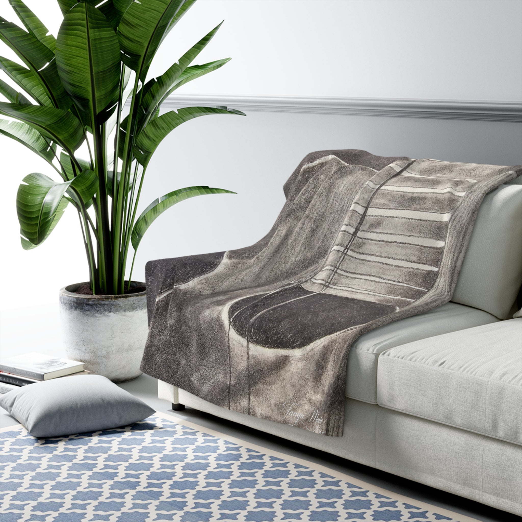 Sherpa-style blanket with gray acoustic guitar artwork, draped over a light sofa arm
