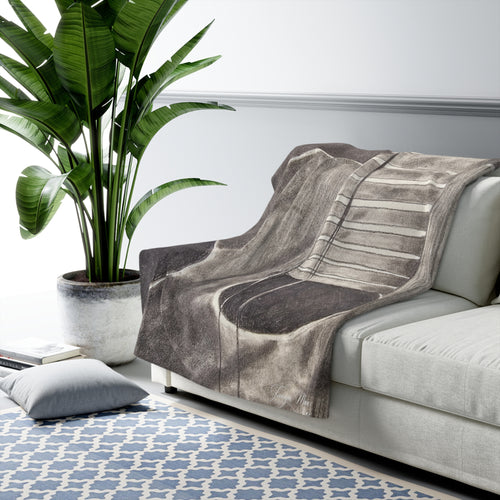 Sherpa-style blanket with gray acoustic guitar artwork, draped over a light sofa arm