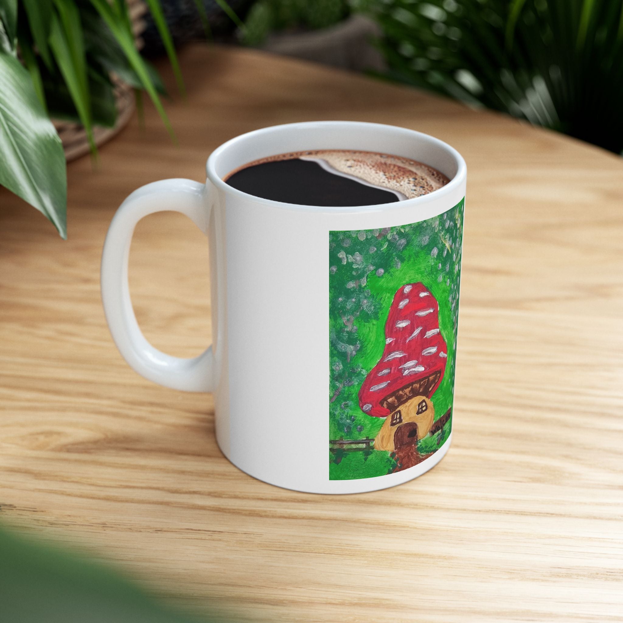 White ceramic mug with red mushroom house artwork and filled coffee inside