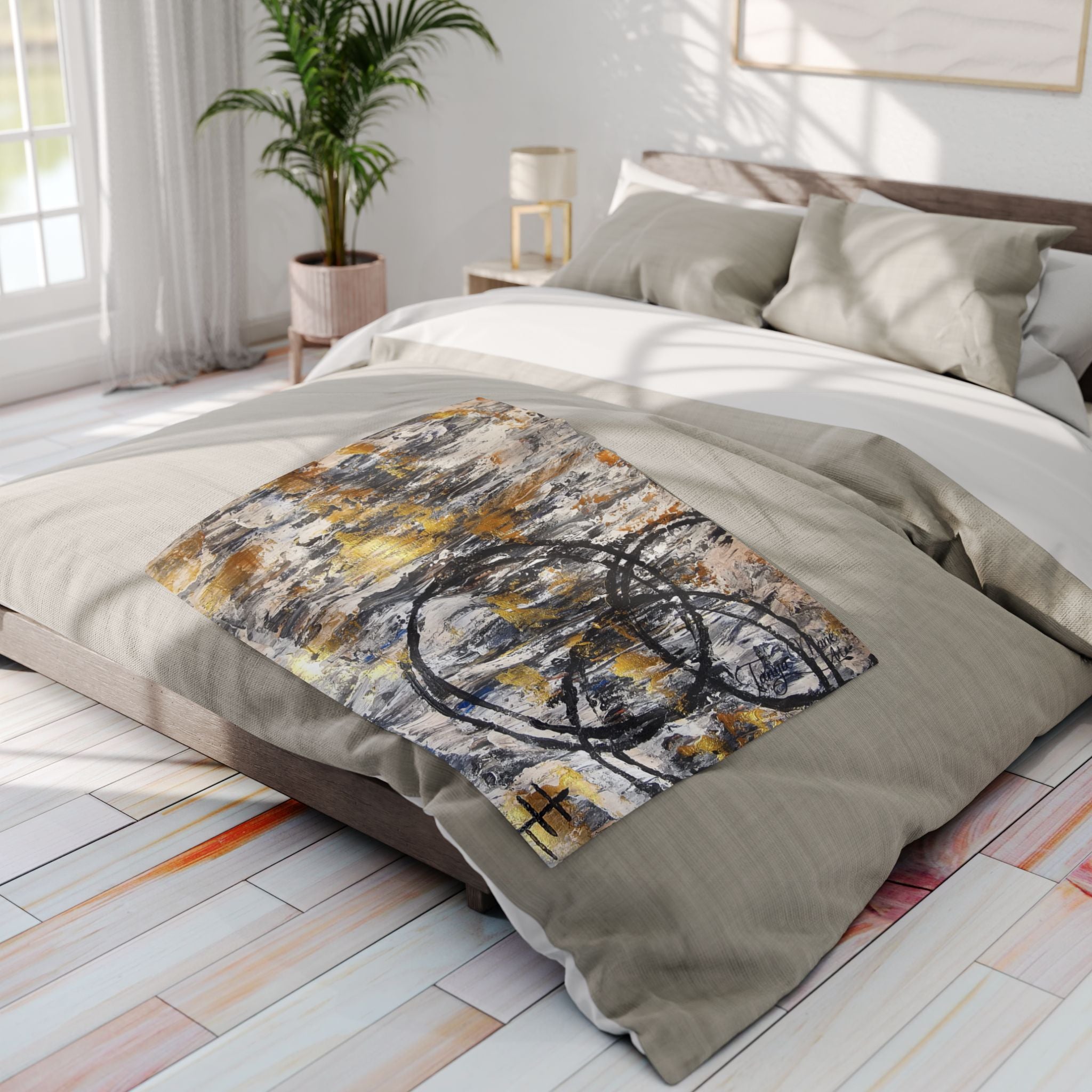 Fleece throw blanket with grey, gold, and black abstract circle design on bed surface