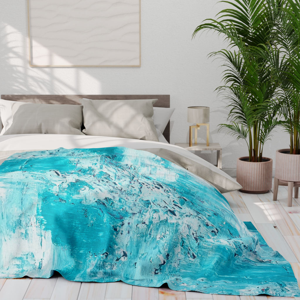 Turquoise abstract fleece blanket on bed, spread across duvet with splash pattern