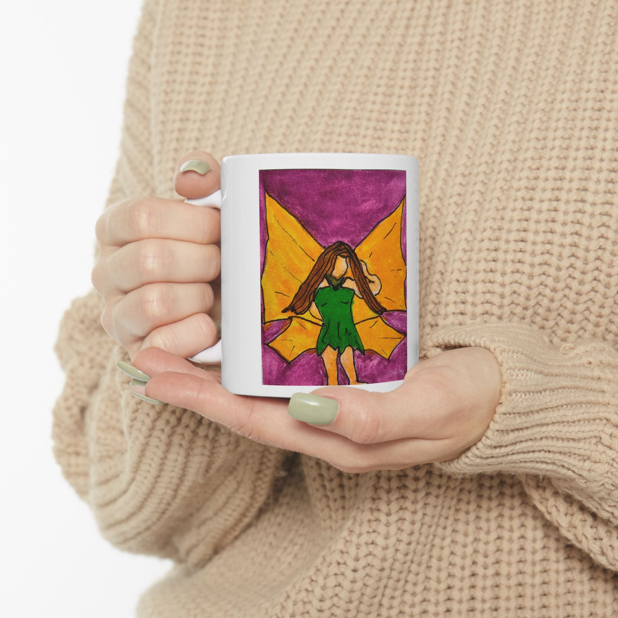 White ceramic mug held in hands, featuring a hand-drawn fairy wing watercolor panel.