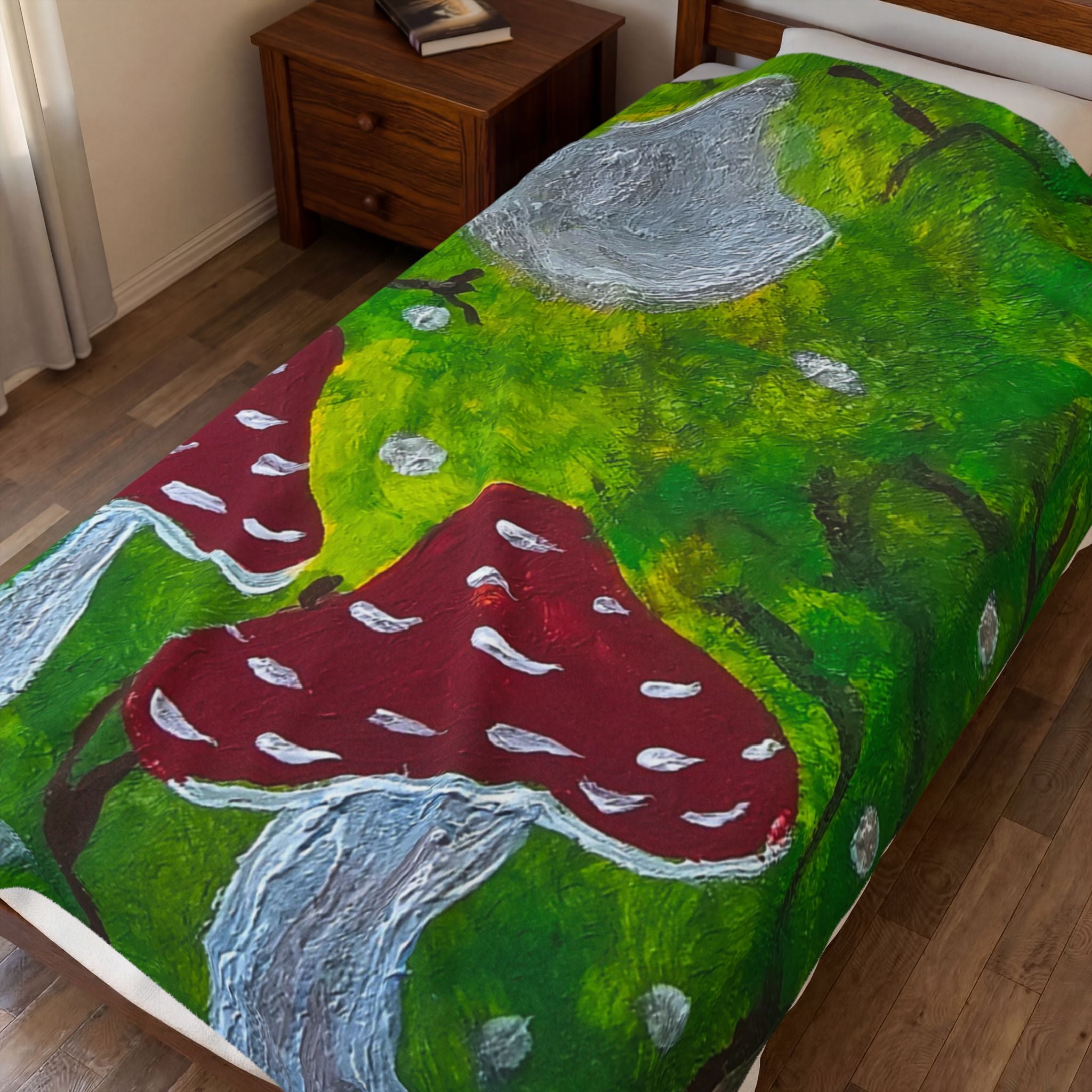 Plush velveteen blanket with green forest artwork, red mushrooms, and gray rock