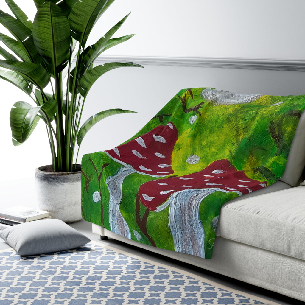 Sherpa blanket throw with green forest pattern, red mushrooms, and gray branches, laid on sofa