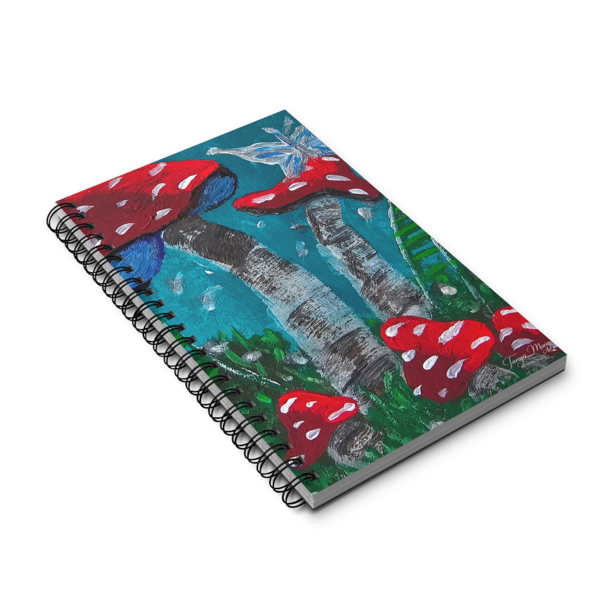 Closed spiral notebook with mushroom artwork cover, red toadstools on teal forest scene
