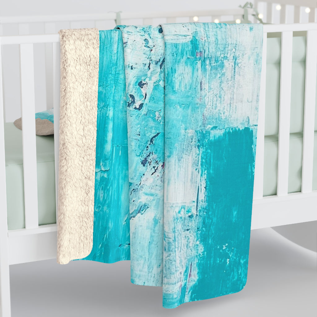 Sherpa blanket draped with off-white fuzzy edge and turquoise abstract front panel