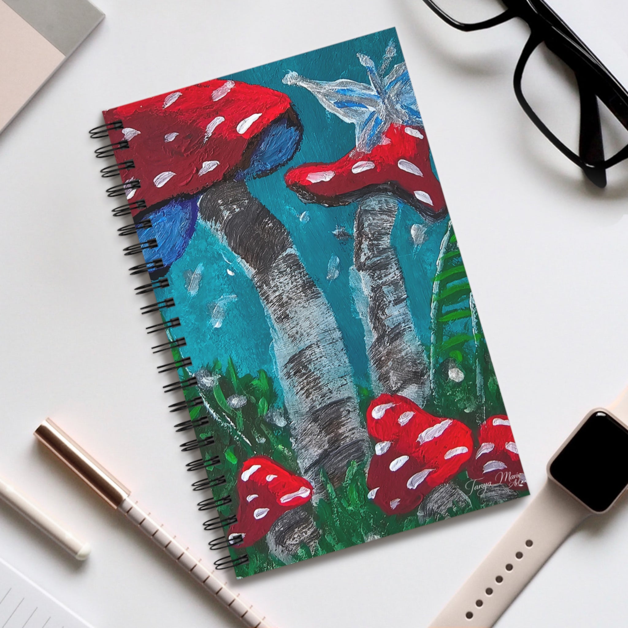 Spiral notebook cover featuring red toadstool mushrooms and teal forest painting
