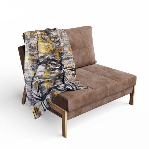 Fleece blanket with abstract grey, gold, and black circle artwork over a sofa