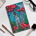 Spiral notebook with red toadstool forest cover art, blue-green background and mushrooms.