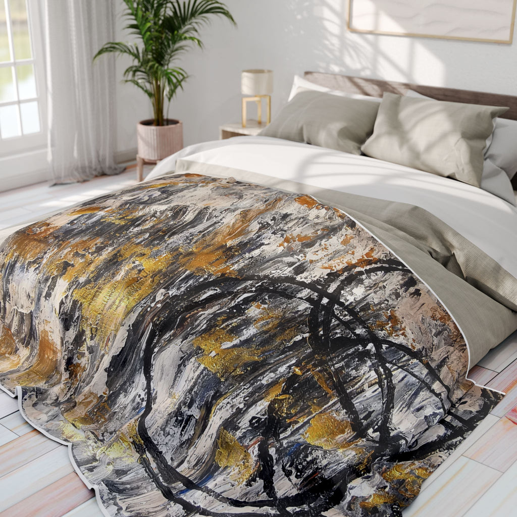Abstract fleece throw blanket on bed with grey, black, white, and gold swirl pattern
