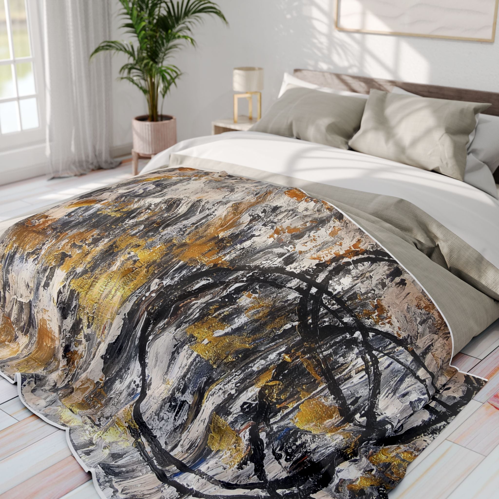 Abstract fleece throw blanket on bed with grey, black, white, and gold swirl pattern