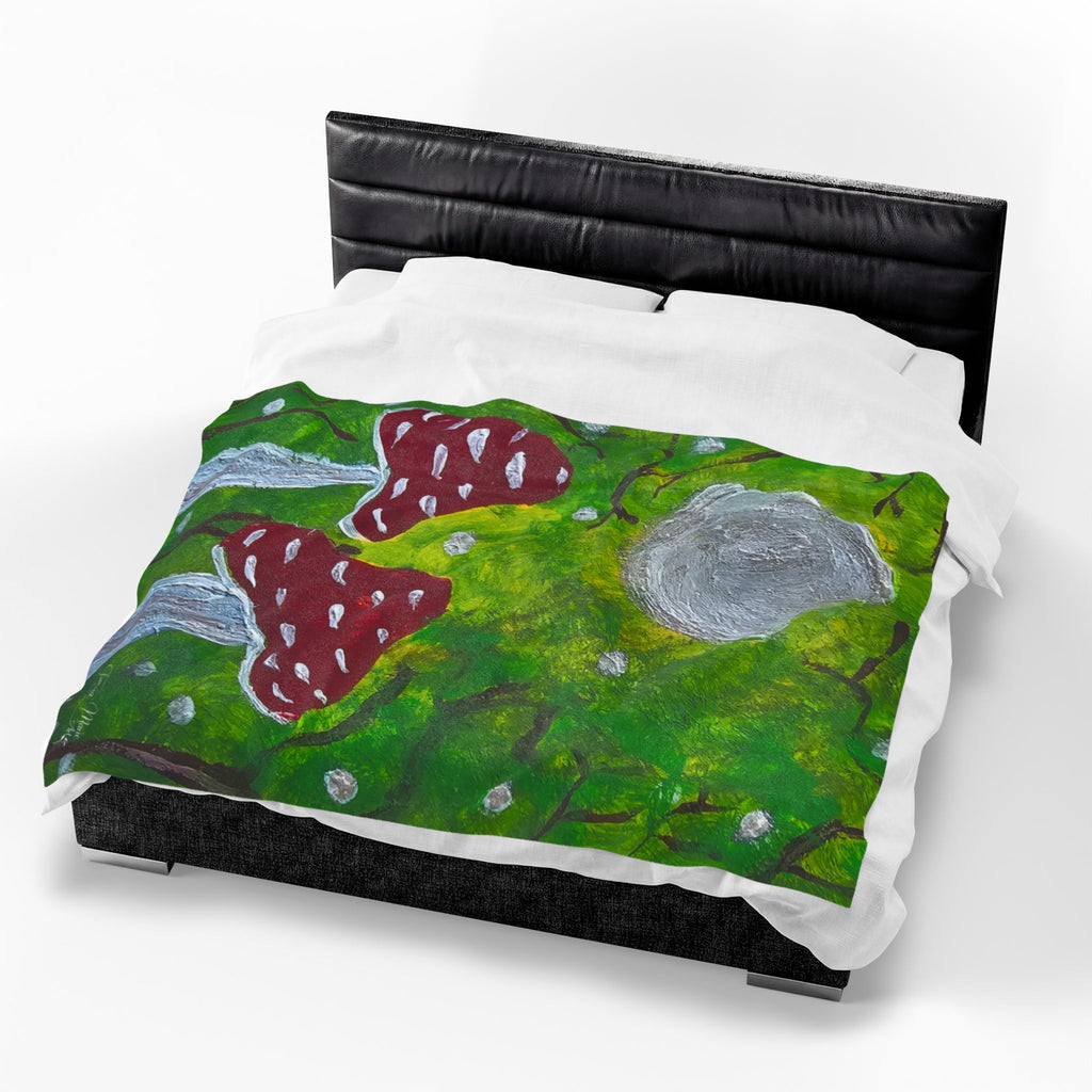 Plush velveteen blanket with green woodland print, red spotted mushrooms, and gray boulders