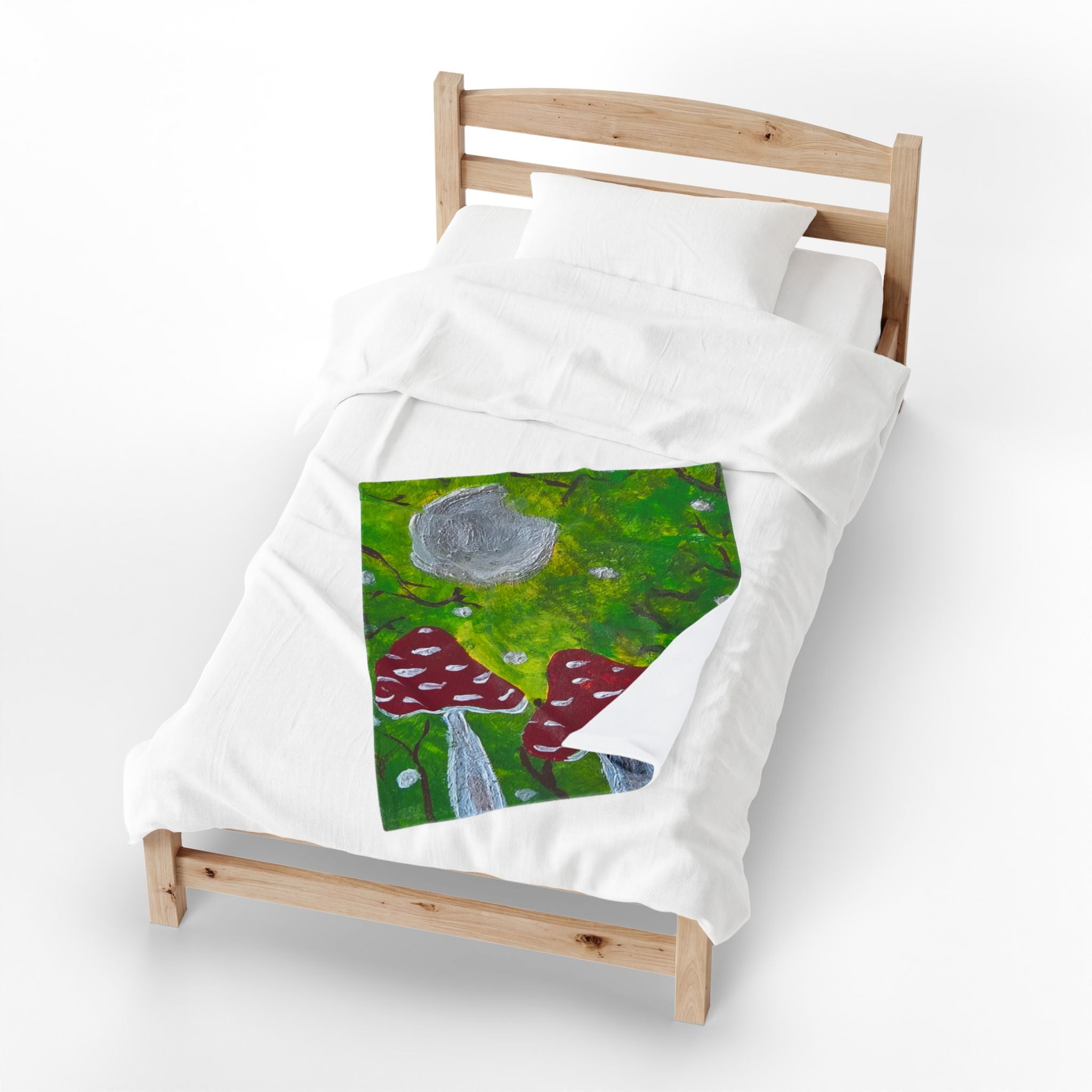 White plush blanket with stitched green forest art, red mushroom caps, gray moon.