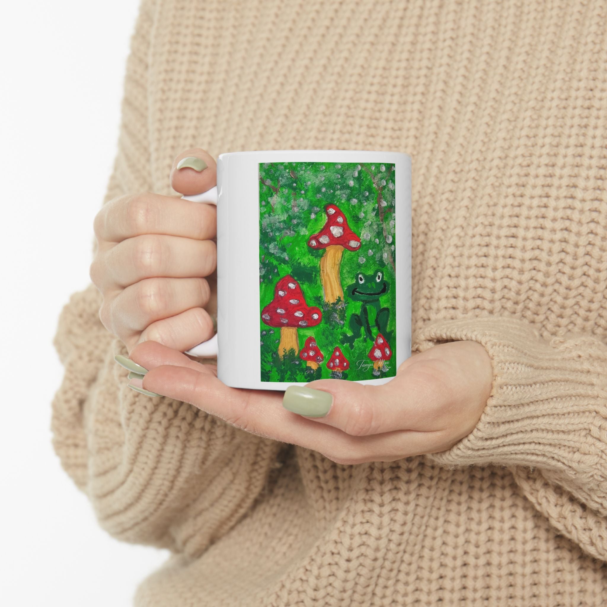 White ceramic mug with colorful forest frog and red mushrooms artwork on front