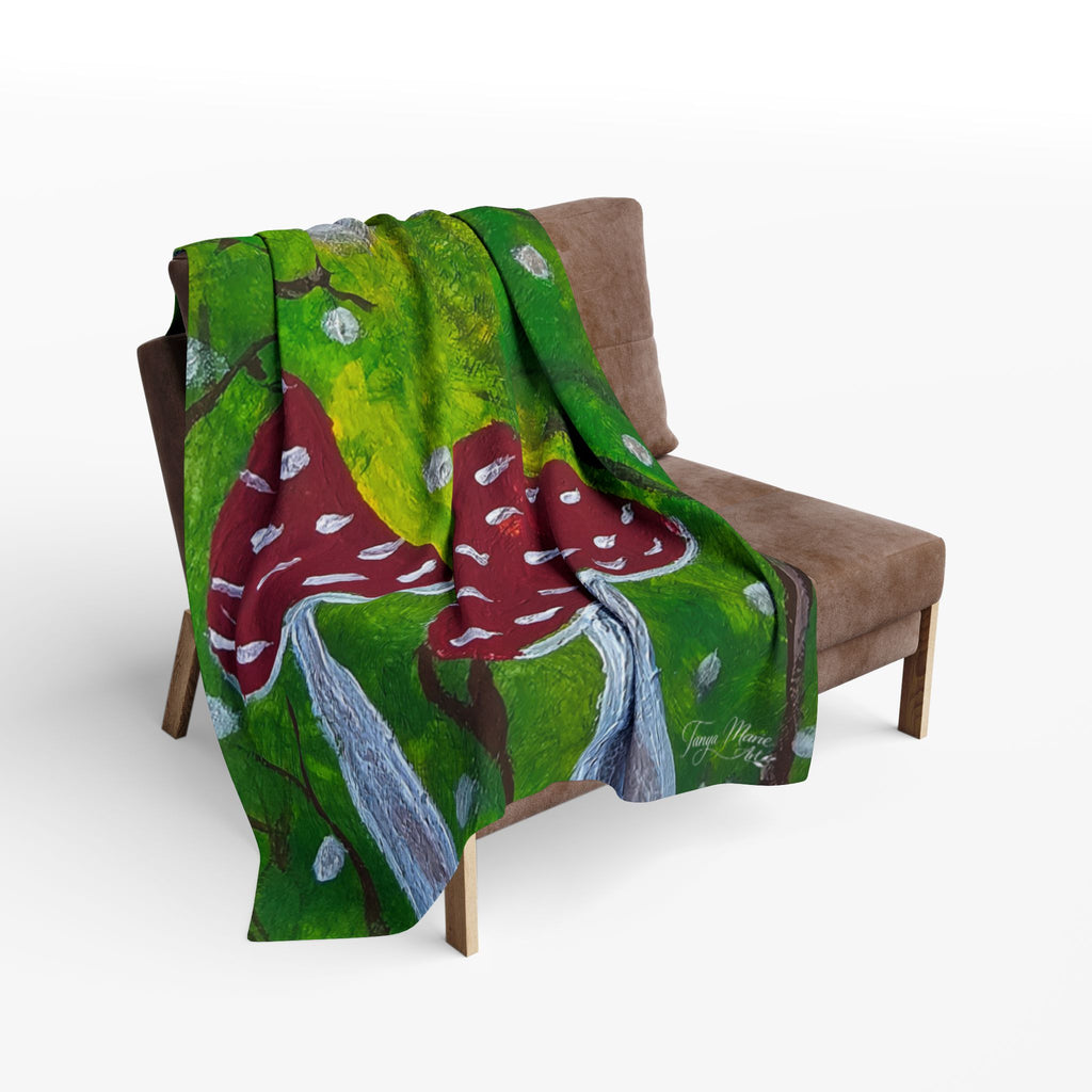 Green fleece blanket with red spotted mushrooms and gray moonlike cap artwork