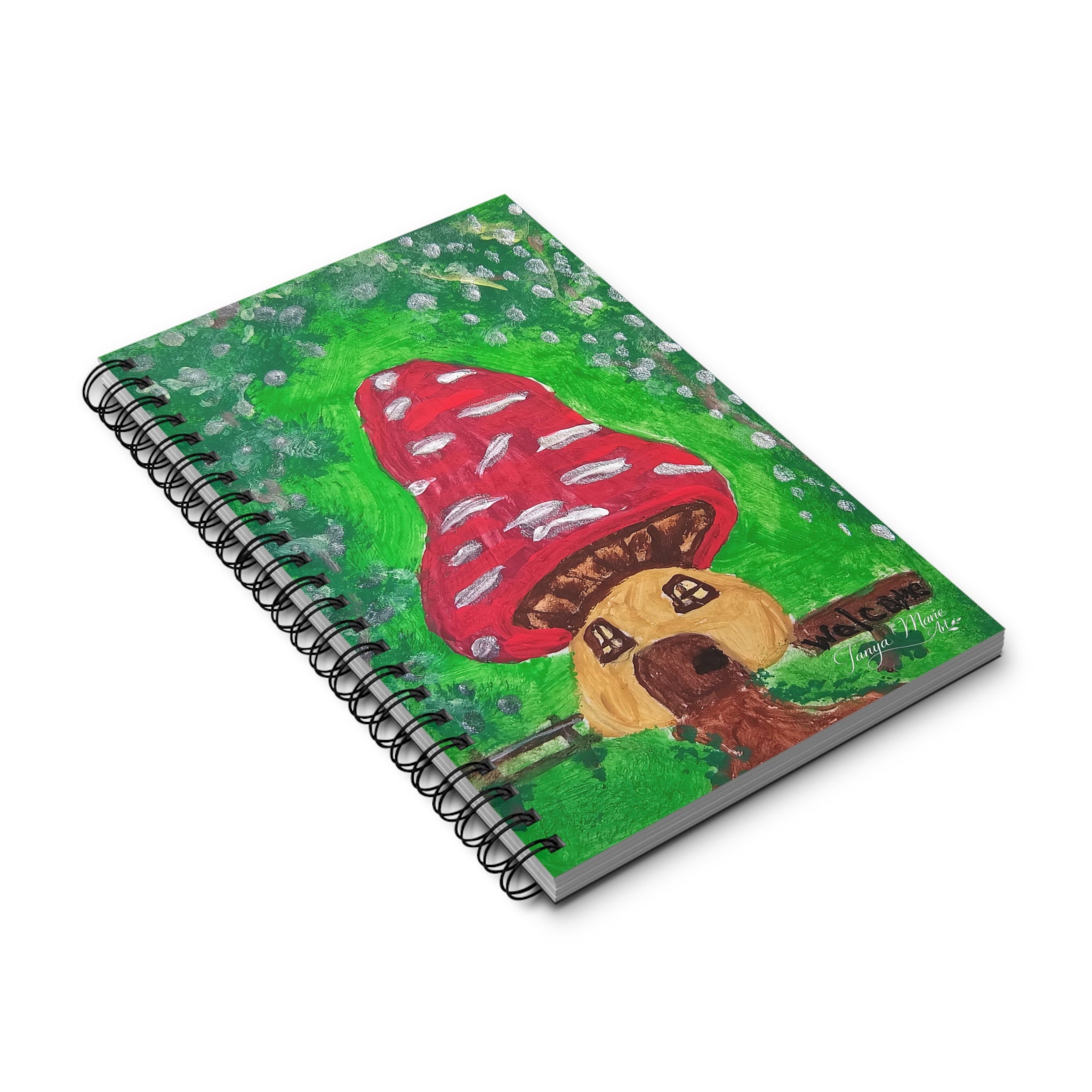 Spiral-bound notebook angled view with red mushroom house cover and green speckled background
