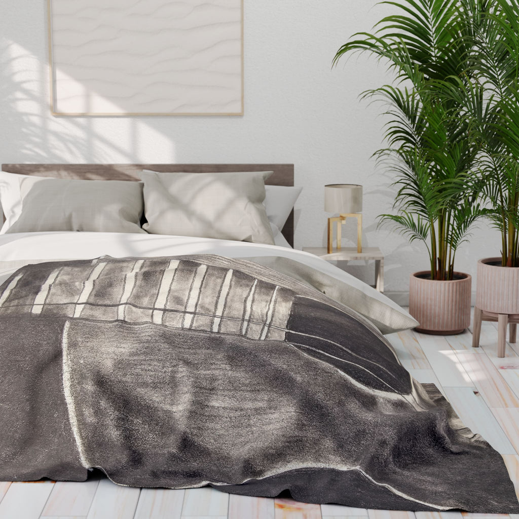 Gray fleece blanket on bed with acoustic guitar graphic across top
