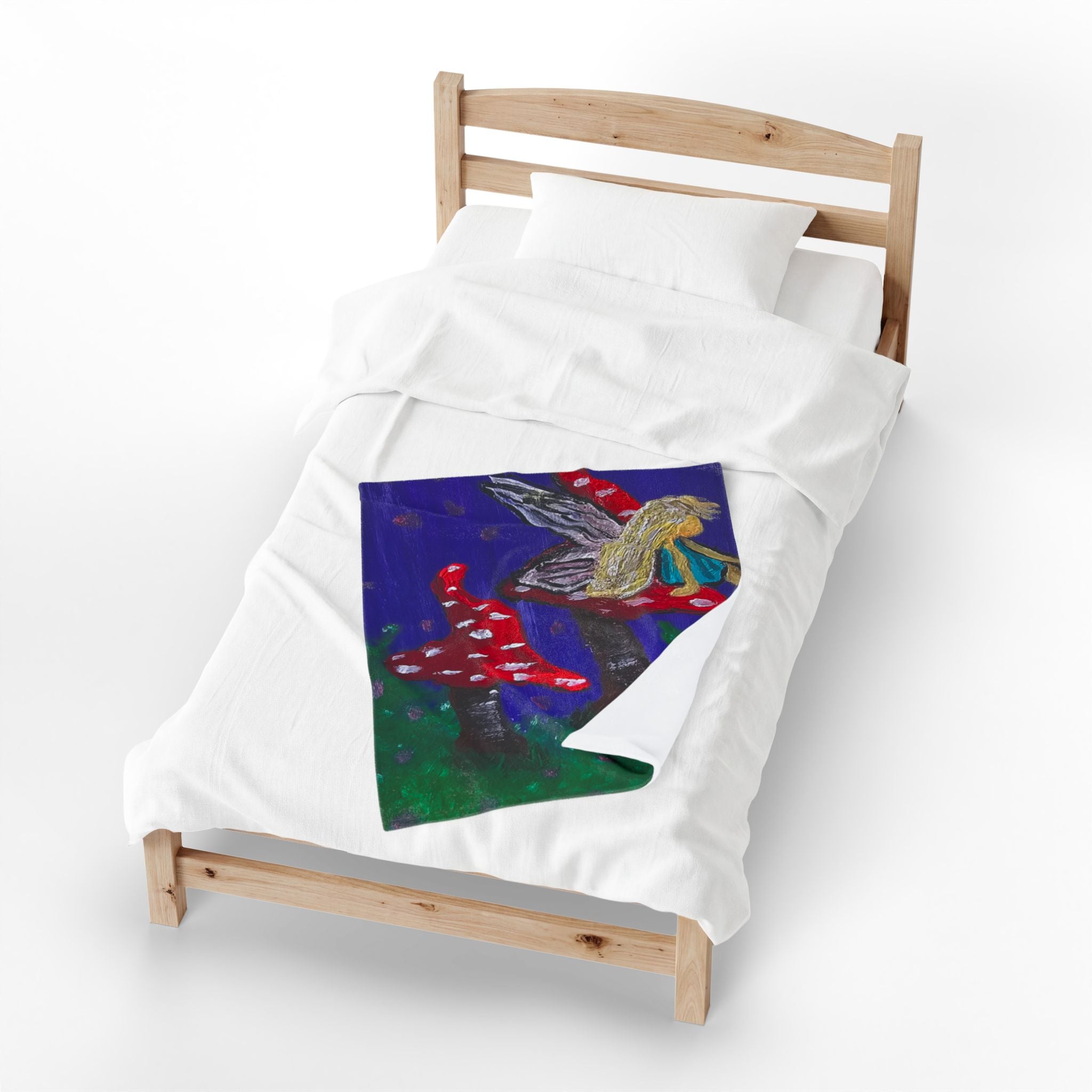 White plush throw blanket with colorful fairy and red toadstool art on bed