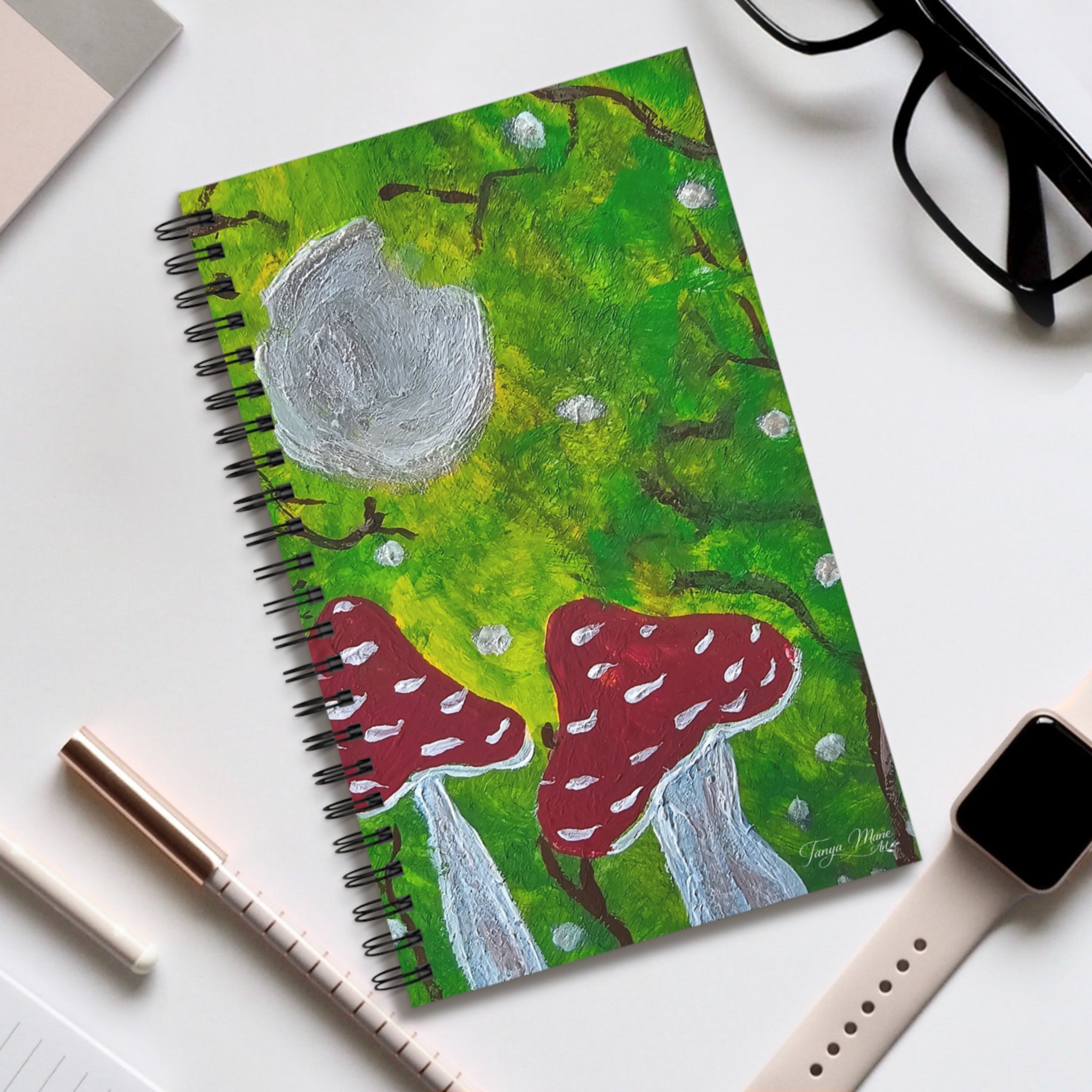 Spiral journal notebook with green forest cover, red mushrooms, gray moon, and black binding