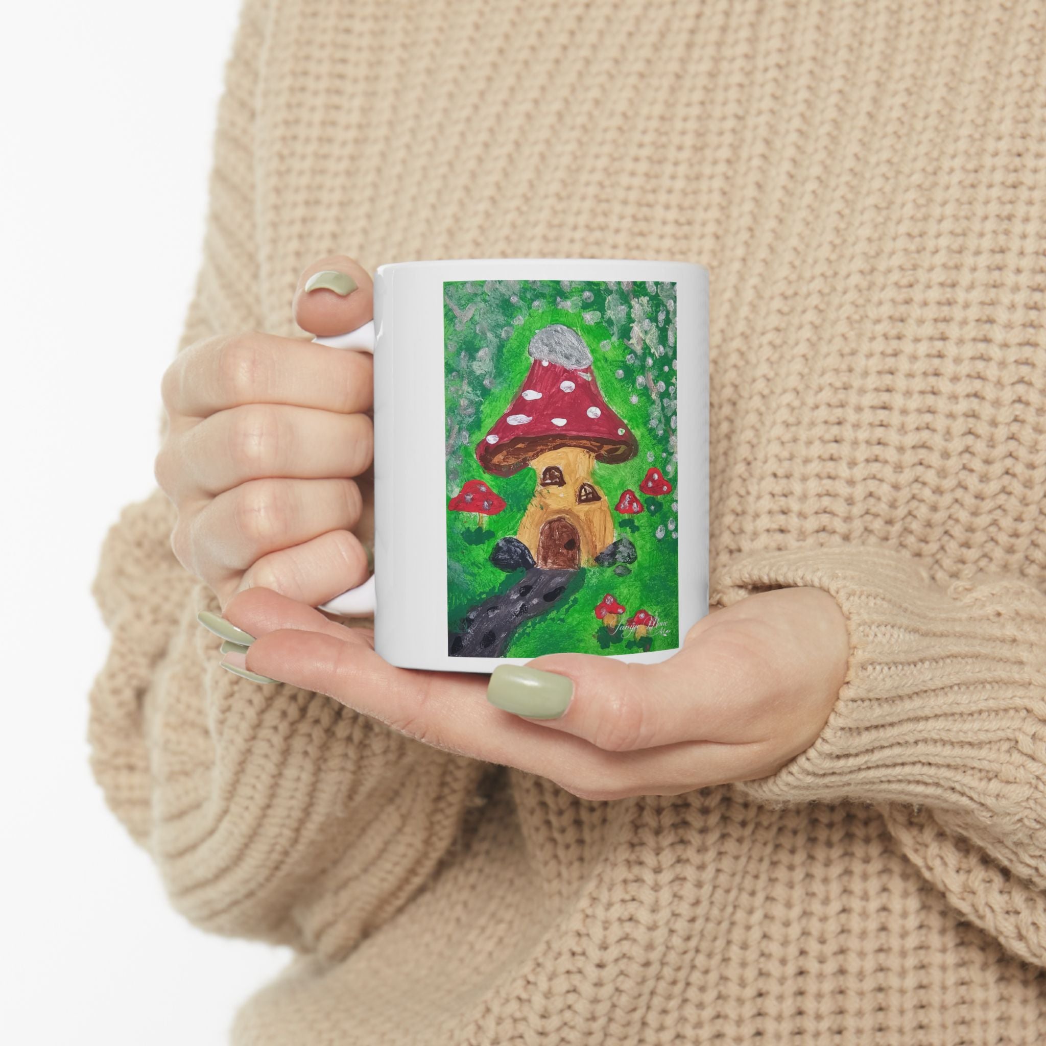 White ceramic mug with colorful mushroom cottage scene illustration on front
