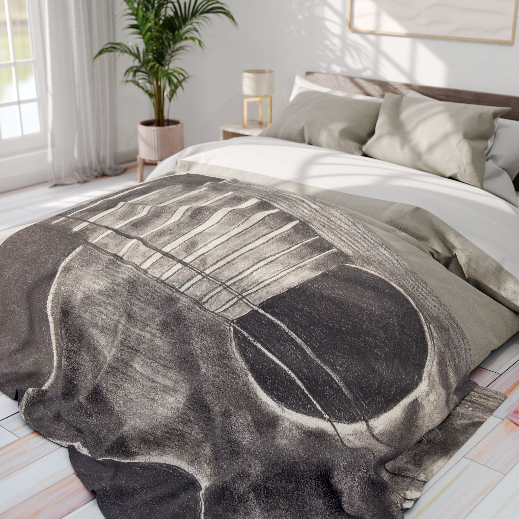 Gray fleece blanket on bed, acoustic guitar sketch centered
