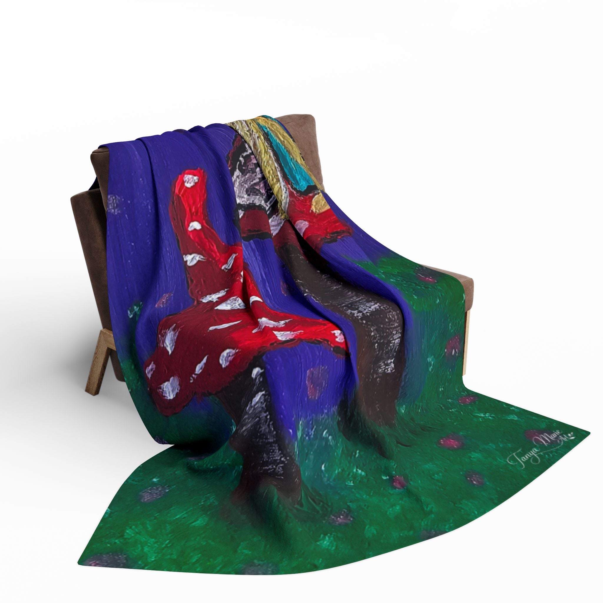 Fleece throw blanket draped over chair arm with red mushroom and fairy wing artwork