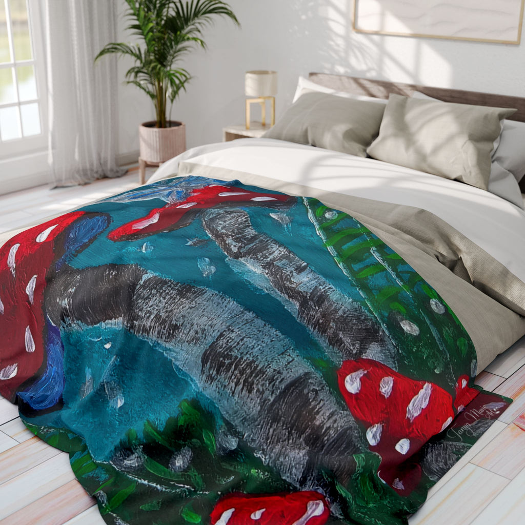 Fleece blanket on bed with teal and green forest print and red mushroom accents across top