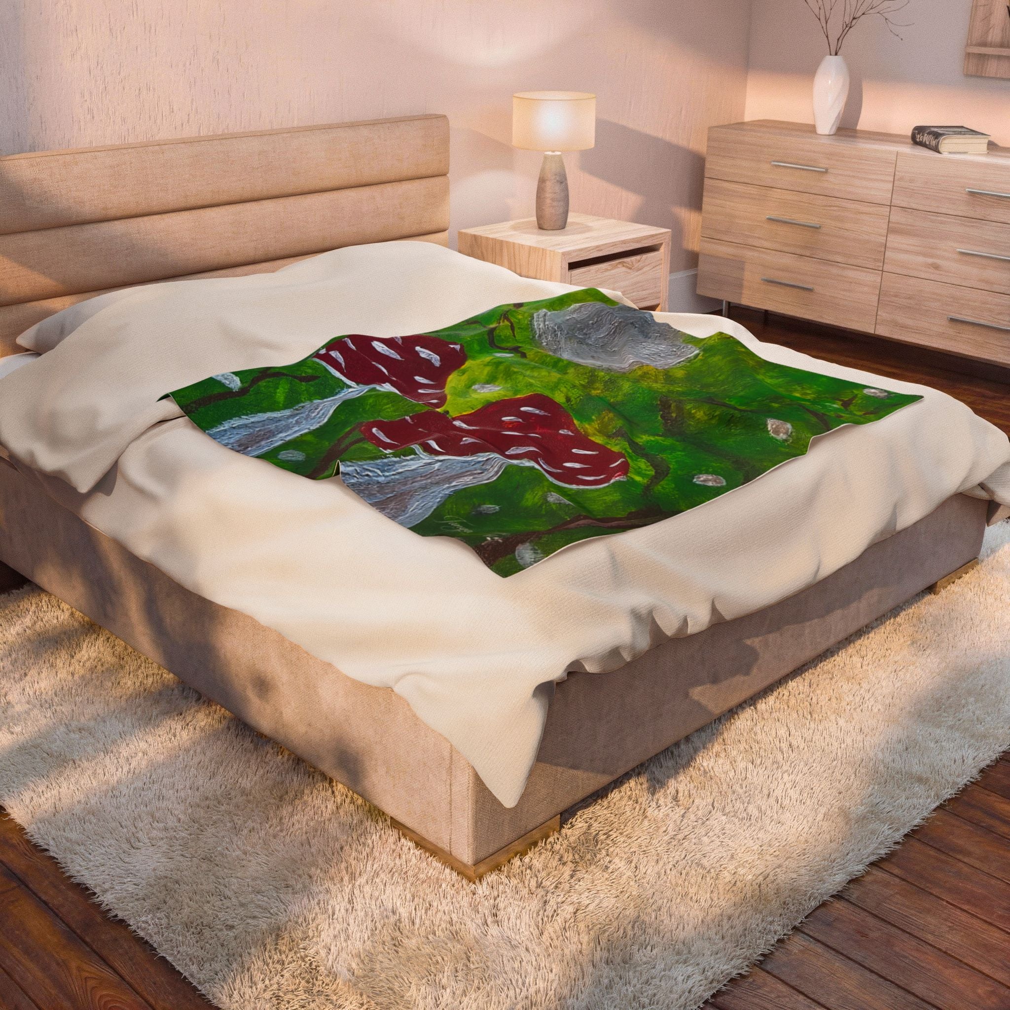 White plush blanket laid over bed with green forest print, red mushrooms, gray moon.