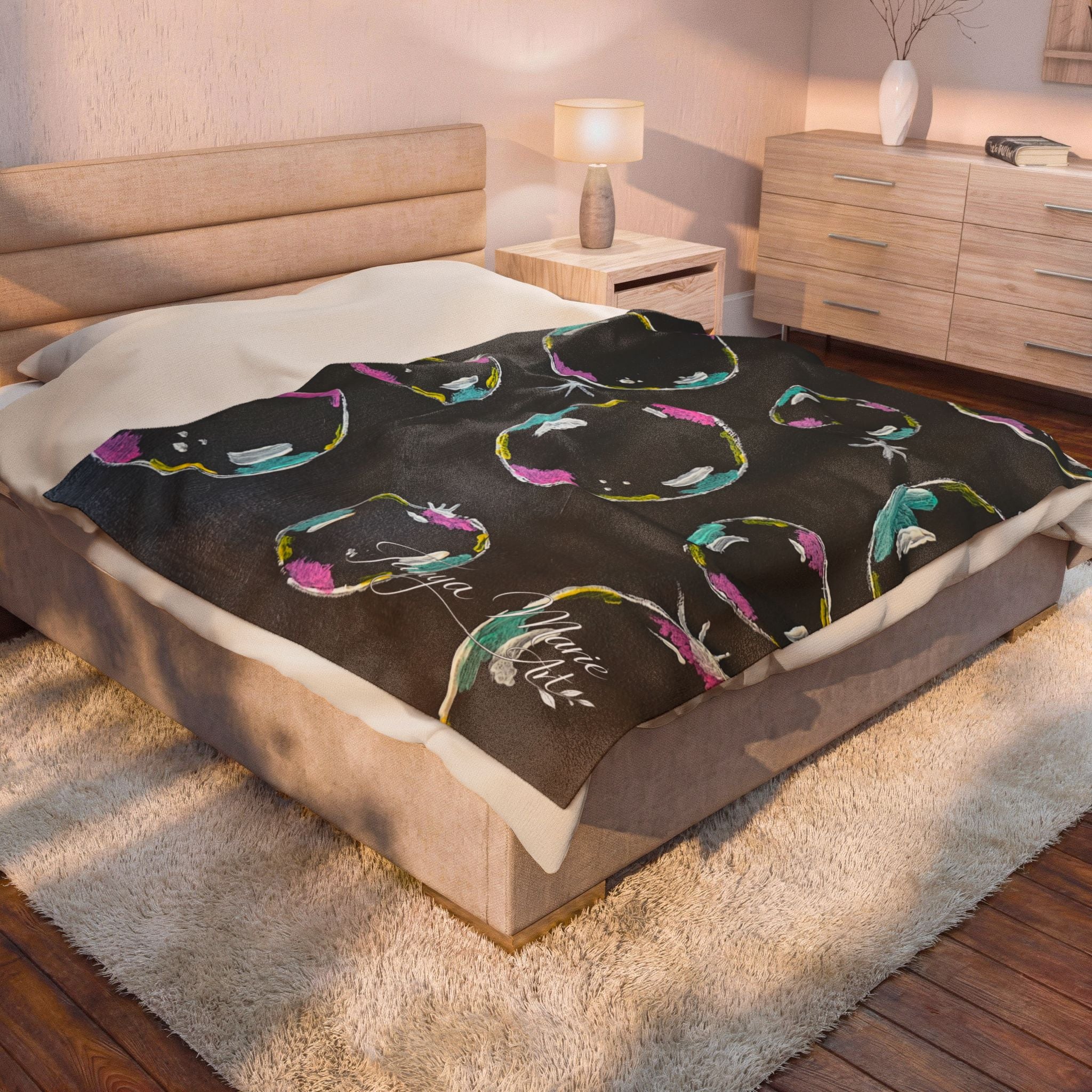 Black velveteen plush blanket with colorful bubble ring pattern on bed